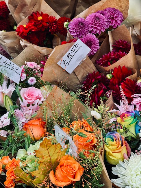 A vibrant array of fresh flower bouquets displayed at a flower shop, featuring a variety of colourful blooms including red dahlias, purple chrysanthemums, pink roses, orange roses, and multicoloured r